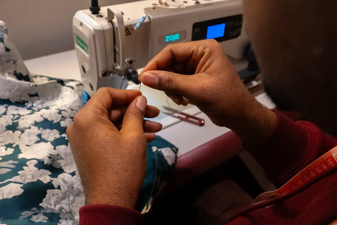 Threading a needle at a Tailor Express sewing station.
